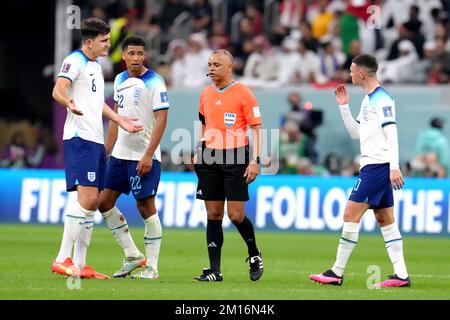 Harry Maguire, de l'Angleterre (à gauche), a des mots avec l'arbitre Wilton Pereira Sampai après qu'il a battu à mi-temps aux côtés de ses coéquipiers Jude Bellingham et Phil Foden, (à droite) lors du match de quart-finale de la coupe du monde de la FIFA au stade Al Bayt d'Al Khor, au Qatar. Date de la photo: Samedi 10 décembre 2022. Banque D'Images