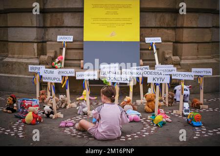 Une fille ukrainienne regarde plusieurs animaux en peluche sur le sol et des placardes portant les noms de différentes villes ukrainiennes, symbolisant les premières villes qui ont été attaquées par l'armée russe, ainsi que les enfants qui sont morts, violés et torturés pendant les six premiers mois de guerre. Les Ukrainiens se sont rassemblés sur la Plaza del Castillo à Pampelune, dans le nord de l'Espagne, le jour de leur indépendance de l'URSS. Banque D'Images