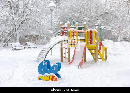 Neige dans le parc urbain en hiver, Moscou, Russie. Ville déserte en chute de neige, vue panoramique sur un terrain de jeu vide enneigé. Thème du froid et du gel, wintry nous Banque D'Images