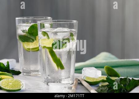 Cocktails mojito rafraîchissants d'été avec citron vert et menthe sur un plateau en bois blanc Banque D'Images