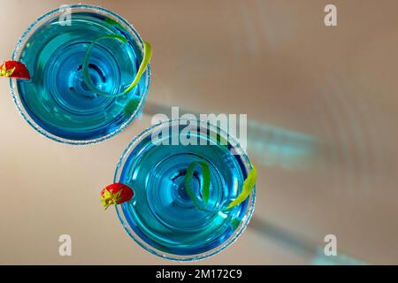 Deux verres avec cocktail de margarita bleue garni de zeste de lime et de fraises, foyer sélectif. Banque D'Images
