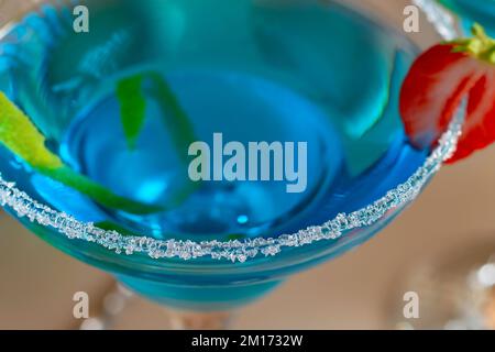 Verre avec cocktail de margarita bleue garni de zeste de lime et de fraises, concentration sélective. Banque D'Images