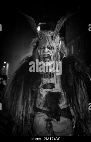 Les monstres masqués de diable défilent dans le village en écartant la foule tout en gardant vivante cette tradition alpine folklorique Banque D'Images