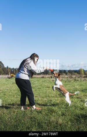 Grande jeune femme jouant avec son chiot et appréciant le moment dans la nature. Jouets pour animaux Banque D'Images
