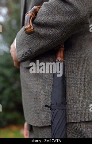 Détail de gentleman avec un parapluie à manche en bambou à Londres, Royaume-Uni .Un parapluie de gentleman très élégant avec une poignée en bambou traditionnelle. Banque D'Images