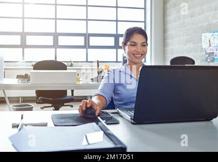 Le sourire qui vient d'avoir une carrière réussie. Photo d'une jeune femme d'affaires utilisant un ordinateur portable au travail. Banque D'Images