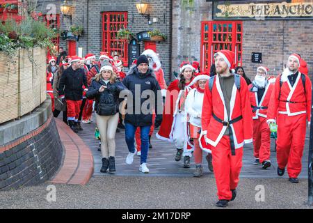 Londres, Royaume-Uni, 08th décembre 2022. Le groupe passe devant « The Anchor », l'un des plus anciens pubs de Londres sur la Tamise. Les Santas marchent à travers Borough Market et le long de la Tamise sur la rive sud de Londres. Des centaines de Jolly Santas se joignent à l'édition 2022 de London SantaCon, un congrès annuel à but non lucratif qui voit les donateurs présents de Laponie marcher le long de diverses routes à Londres qui se rejoignent habituellement à Trafalgar Square. La marche permet de gagner de l'argent pour la charité. Le SantaCon de cette année est plus petit et moins exhuberant que les années précédentes, après plusieurs années d'absence pendant la pandémie de covid. Banque D'Images