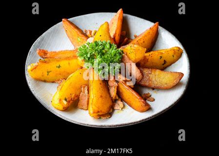 quartiers de pommes de terre rustiques avec bacon sur fond noir vue de dessus Banque D'Images