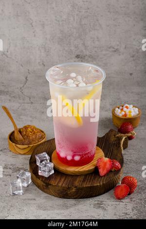 Boba ou perles de tapioca est thé de lait à bulles taïwanais dans une tasse en plastique avec goût de citron fraise sur fond de texture, rafraîchissement d'été. Banque D'Images