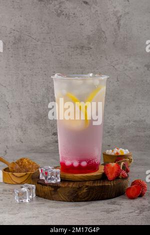 Boba ou perles de tapioca est thé de lait à bulles taïwanais dans une tasse en plastique avec goût de citron fraise sur fond de texture, rafraîchissement d'été. Banque D'Images