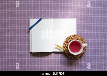 Ouvrez le carnet et le crayon de couleur, tasse de thé noir sur fond de tissu violet à carreaux. vue de dessus, espace de copie Banque D'Images