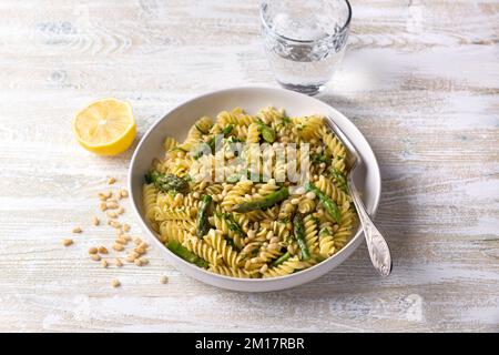 Pâtes végétaliennes aux asperges, à l'ail, aux pignons de pin et au persil sur fond de bois. Plats faits maison simples Banque D'Images