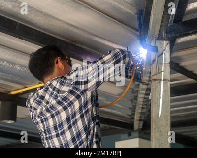Un soudeur travaille sur un châssis en acier. Sur le chantier. Banque D'Images