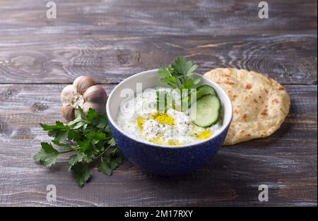 Sauce tzatziki traditionnelle au yaourt grec avec concombres et herbes sur fond de bois, espace Banque D'Images