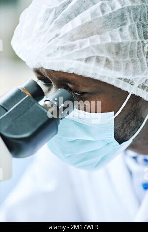 Portrait vertical de scientifique noir regardant au microscope, gros plan Banque D'Images