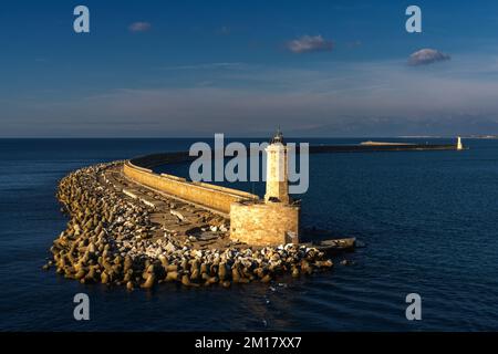 Mur du port en pierre et jetée avec phare dans la lumière chaude du matin dans le port de Livourne Banque D'Images