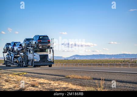 Semi-camion de transport de voitures blanc classique industriel avec pièces chromées transportant des voitures sur semi-remorque modulaire hydraulique spéciale à deux niveaux Banque D'Images