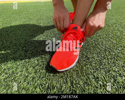 Tyumen, Russie-13 août 2022: Chaussures de course à pied Adidas, pelouse artificielle de couleur corail orange, course de eq21. Logo. Banque D'Images