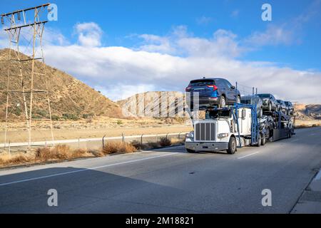 Semi-camion de transport de voitures blanc classique industriel avec pièces chromées transportant des voitures sur semi-remorque modulaire hydraulique spéciale à deux niveaux Banque D'Images