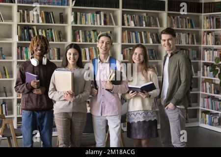 Heureux étudiants divers posant pour le portrait de groupe dans la bibliothèque Banque D'Images