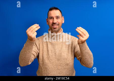 Hispanique homme environ 40s avec la barbe debout sur fond bleu isolé faisant le geste italien avec les mains et les doigts expression confiante. Banque D'Images