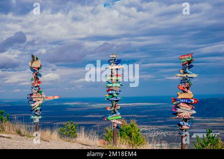 Pyatigorsk, Russie. 2022, 24 octobre. Direction vers différents endroits du monde indiqué dans un panneau de rue. Paysage sur le poste de montagne avec des villes de pointeurs et banc en bois sur le sommet Banque D'Images