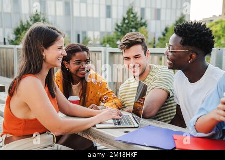 Groupe multiethnique de jeunes étudiants souriants et heureux préparant un examen et faisant des travaux à domicile, partageant différentes idées en utilisant leurs ordinateurs portables dans une communication positive et amicale sur le campus. Concept d'éducation. Photo de haute qualité Banque D'Images