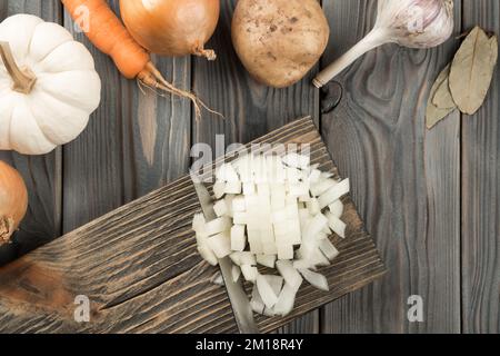 Couper l'oignon épicé avec un couteau en cubes sur la planche à bois de la cuisine. Oignon blanc coupé en dés. Vue de la mise à plat. Disposition des légumes frais crus. Préparez les ingrédients Banque D'Images