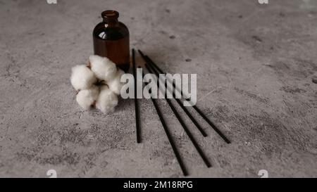 Diffuseur d'arôme avec coton. Aromathérapie sur fond de marbre foncé. Bâtonnets et bouteille en verre avec fleur de coton Banque D'Images