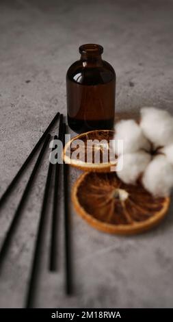 Bouteille transparente de diffuseur d'arôme. Parfum pour la maison avec fleurs de coton, fruits d'orange. Concept tendance, matériaux naturels. Formation à la fabrication de parfums Banque D'Images