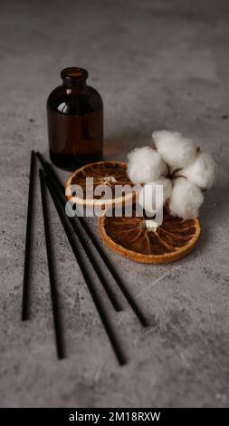 Bouteille transparente de diffuseur d'arôme. Parfum pour la maison avec fleurs de coton, fruits d'orange. Concept tendance, matériaux naturels. Formation à la fabrication de parfums Banque D'Images