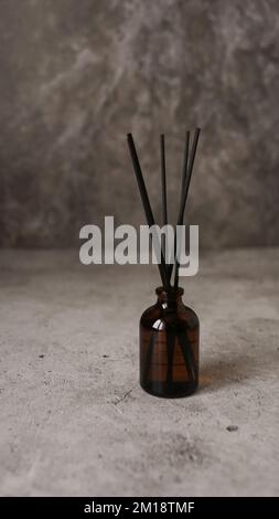 Flacon diffuseur en roseau aromatique avec bâtonnets noirs. Parfum pour la maison. Concept de tendance. Photo verticale sur fond de marbre Banque D'Images