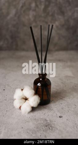 Bouteille transparente de diffuseur d'arôme. Parfum pour la maison avec fleurs de coton. Concept tendance, matériaux naturels. Photo verticale sur fond de marbre Banque D'Images