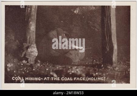 Extraction du charbon - au niveau de la face du charbon (holing). Photo du début du 20th siècle d'un mineur allongé sur le sol entre deux puits de bois, travaillant sur la face de charbon. L'image est l'une des photos publiées sous forme de cartes postales par M. Brookes de Pontypridd, au sud du pays de Galles Banque D'Images