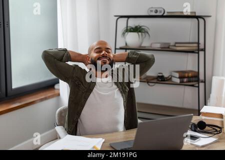 Portrait d'un entrepreneur latino-américain heureux qui se détend sur le lieu de travail et se penche en arrière sur la chaise avec les mains derrière la tête Banque D'Images