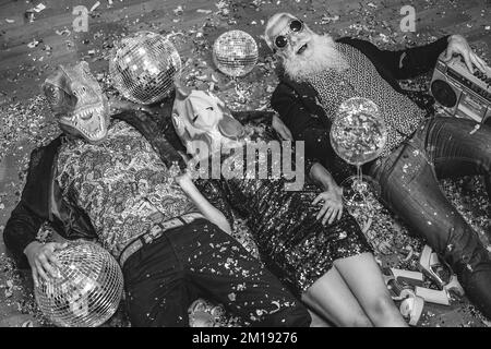 Des gens fous célébrant la fête du carnaval à l'intérieur de la boîte de nuit - Focus sur le masque de poulet - montage noir et blanc Banque D'Images