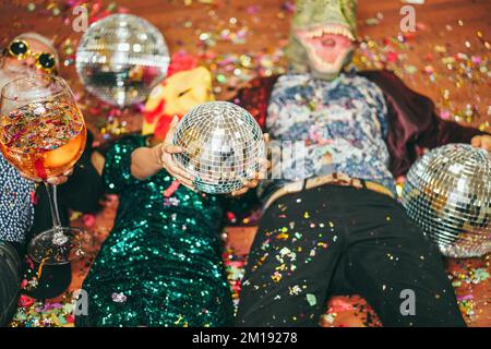 Des gens fous célébrant la fête du carnaval à l'intérieur de la boîte de nuit - concentrez-vous sur les mains tenant le bal disco Banque D'Images