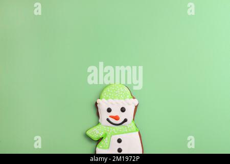 pain d'épice bonhomme de neige sur fond vert. Joyeux cookie de Noël. décoration douce et souriante Banque D'Images