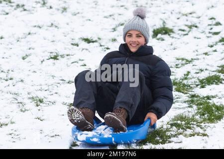 Chippenham, Wiltshire, Royaume-Uni, 11th décembre 2022. Alors que les habitants de Chippenham se réveillent devant leur première neige de l'année, une femme est photographiée dans un parc local de Chippenham alors qu'elle descend une colline sur un traîneau. Credit: Lynchpics/Alamy Live News. Banque D'Images
