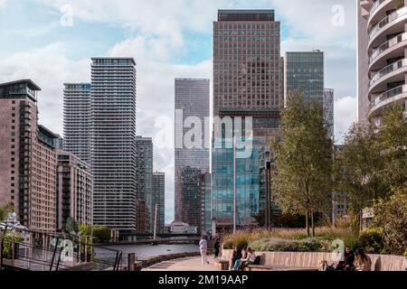 Les gens s'assoient et parlent sur des bancs et marchent sur la promenade avec des gratte-ciel en arrière-plan à Harbour Quay Gardens, Wood Wharf, Canary Wharf, Londres Banque D'Images