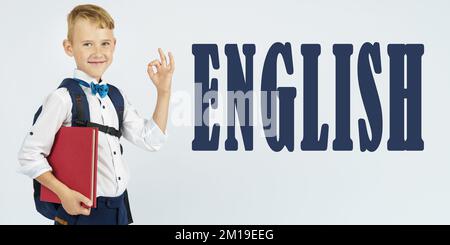 Concept d'éducation. Un écolier avec une mallette tient des livres dans ses mains et montre le geste ok. Le texte est écrit à côté - ANGLAIS Banque D'Images