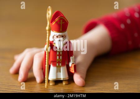 Main d'un jeune enfant tenant une figure Duplo du Saint Nicolas (Sankt Nikolaus), faisant partie de la tradition germanique le 6th décembre Banque D'Images