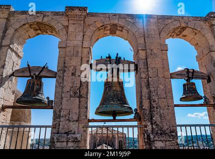 Trois cloches d'une ancienne église sicilienne se distinguent contre un ciel bleu vif illuminé par les rayons du soleil Banque D'Images