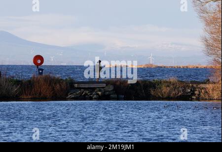 South Shore Lough Neagh, près de Lurgan, comté d'Armagh, Irlande du Nord, Royaume-Uni. 11 décembre 2022. Temps au Royaume-Uni - le froid continue avec des températures tombant à -7C dans certaines parties de l'Irlande du Nord pendant la nuit. Un peu de soleil a fait monter la température jusqu'à environ 4C à l'heure du déjeuner, mais même la brise légère est amèrement froide. Un homme marchant le long de la marina de Kinnego brise-lames lors d'une journée d'hiver ensoleillée avec de la neige dans les montagnes de Sperrin.Credit: CAZIMB/Alamy Live News. Banque D'Images