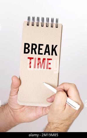 Concept commercial et financier. Un homme tient un stylo et un nœud dans ses mains avec l'inscription - temps de pause Banque D'Images