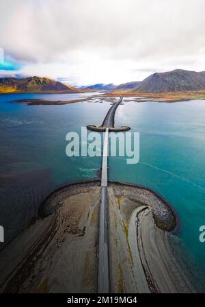 Route pittoresque et pont viking Kolgrafjordur se balançant dans une vaste baie entourée de montagnes escarpées sur la péninsule de Snaefellsnes en Islande Banque D'Images