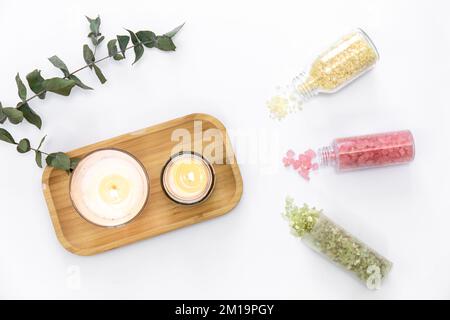 Plat, sel de mer de différentes couleurs et bougies sur fond blanc. Banque D'Images