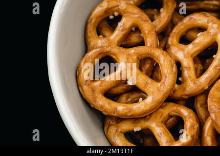 Gros plan, bretzels dans une plaque sur fond noir. Banque D'Images