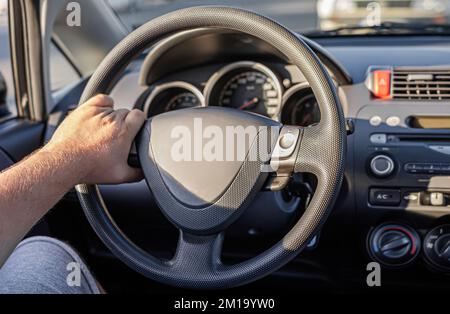 Le conducteur garde les mains sur le volant de la voiture. Banque D'Images