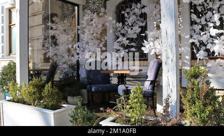 un coin confortable d'un café urbain sur la terrasse avec une table pour deux, des fauteuils confortables, des détails intérieurs en bois et un décor élégant et délicat Banque D'Images